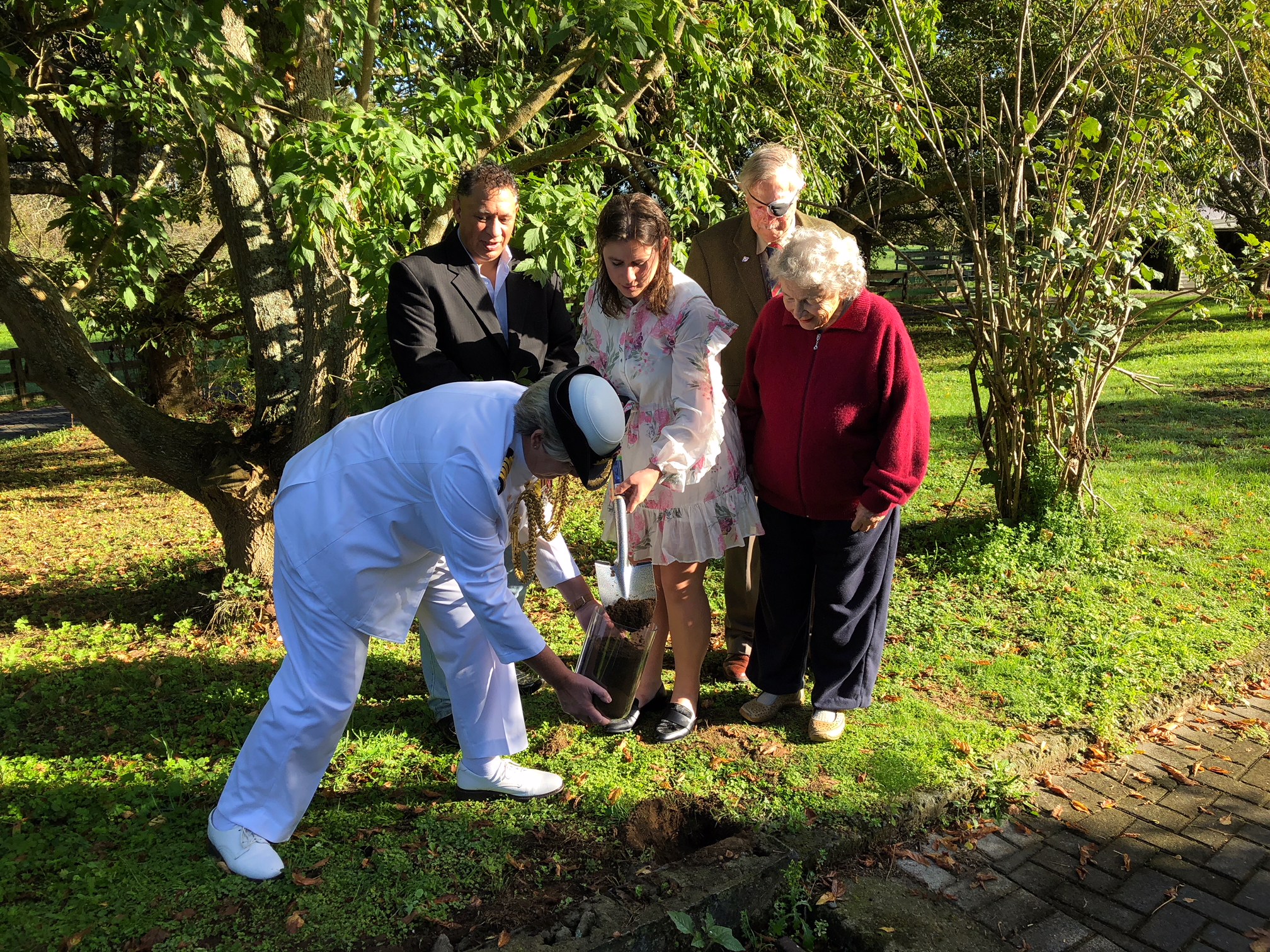 Captain Christine Clarke, of the Royal Australian Navy, collects soil with community members at the Battle of Orakau site in New Zealand.