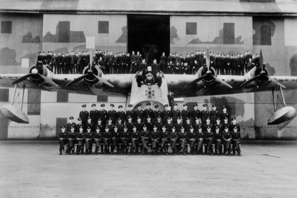 Group portrait of aircrew of 461 Squadron RAAF, with a Sunderland aircraft outside the slipway hangar. AWM P01520.004.