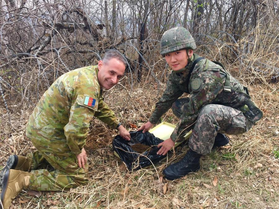 Major Simon Hawkins, Assistant Defence Attache at the Australian Embassy in Seoul, is assisted by a soldier from the 28th Infantry Division of the Army of the Republic of Korea as they collect soil from the battlefield of Maryang San for the Anzac Memorial. Courtesy of Defence Images. 