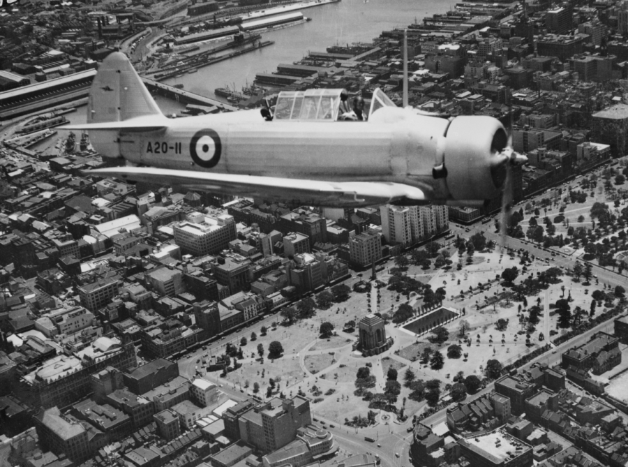 Here, a Wirraway trainer from RAAF Richmond flies over the Anzac Memorial in Hyde Park, 1941.